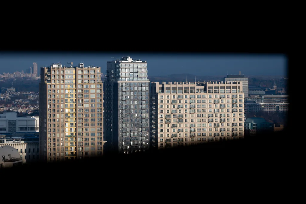 High-rise buildings in low winter sunlight, seen through a narrow dark opening, the city stretching out behind